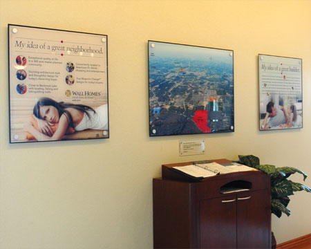 Three square acrylic displays hanging on a wall above an information kiosk