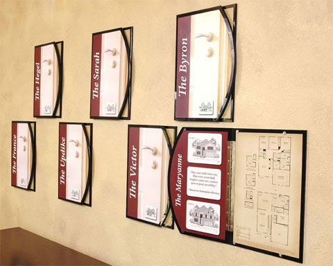 Wall-mounted house floorplans printed on displays designed to look like doors