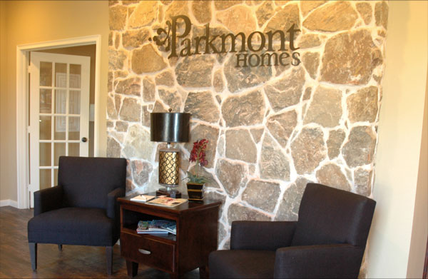 The Parkmont HOmes sales office with two lounge chairs in front of a stone wall