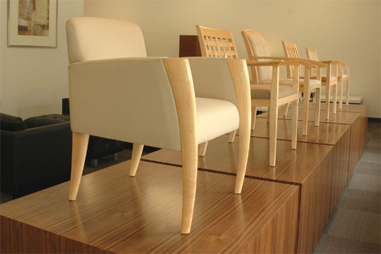 A row of upholstered wood chairs on pedestals at the entrance of the Novikoff Furniture showroom
