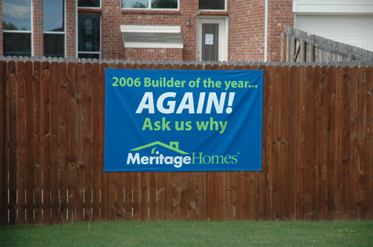 A blue banner mounted on a wood fence