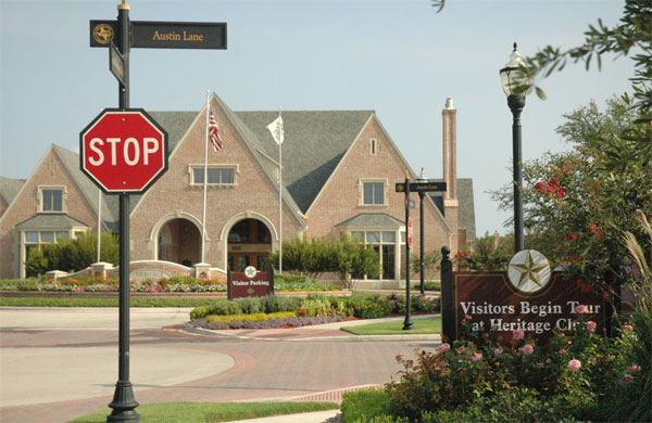 A new home in the Grand Heritage development surrounded by branded signs directing visitors to the sales center