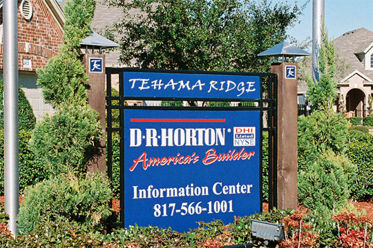 A square blue sign in a black iron frame mounted on wood posts