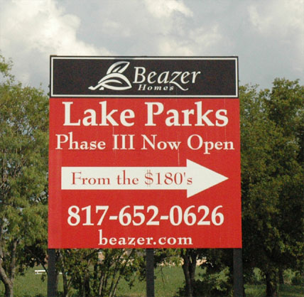 Large red and black directional sign for Beazer Homes with an arrow pointing to the right