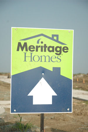 A blue and green Meritage Homes directional sign pointing straight ahead