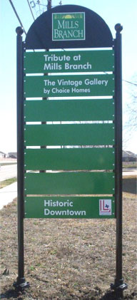 One of the Mills Branch kiosk-style directional signs with green blades mounted on two black posts