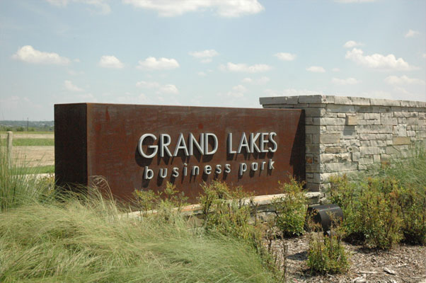 Grand Lakes Business Park monument with aluminum letters mounted to a rust-colored metal box